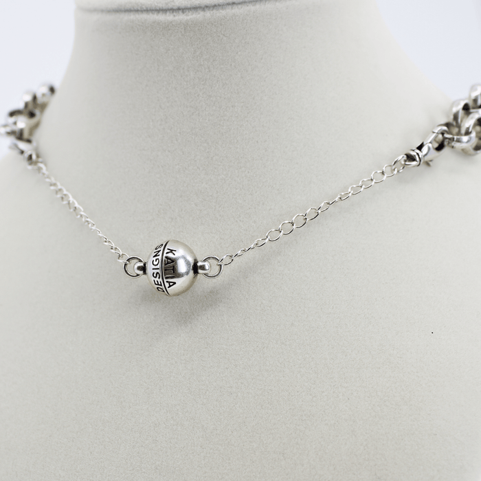 Silver necklace with a round pendant on a mannequin neck against a white background