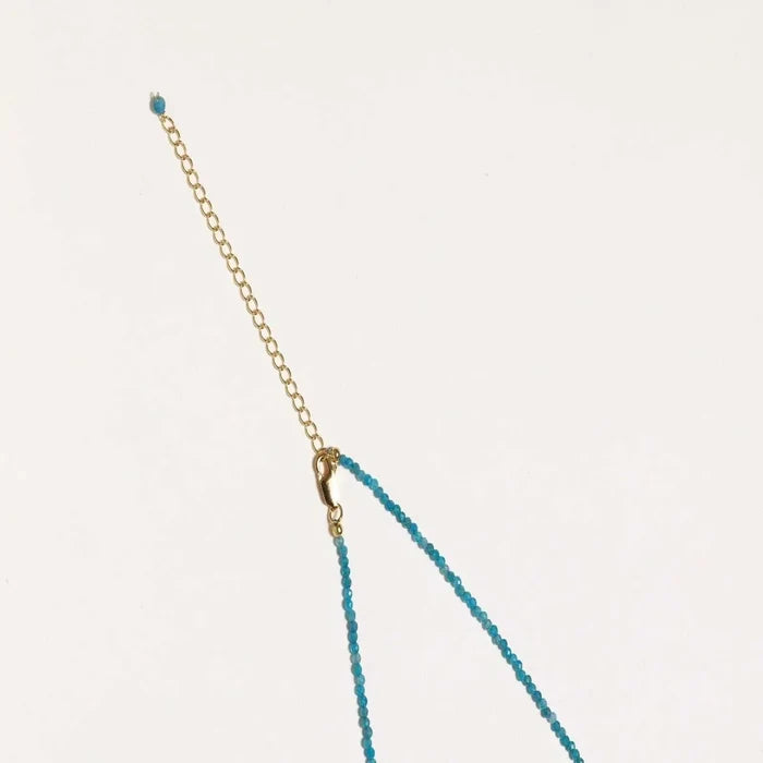 Dainty teal apatite beaded necklace with a single freshwater pearl centerpiece flanked by two small gold beads, adjustable gold clasp.