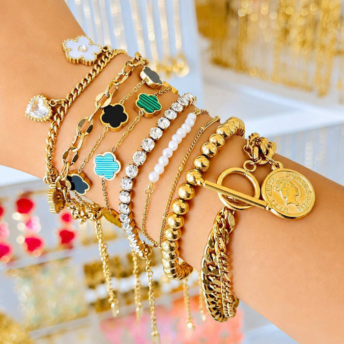 Cubic Zirconia Tennis Bracelet with sparkling white stones set in a slim gold-tone chain, worn among layered bracelets