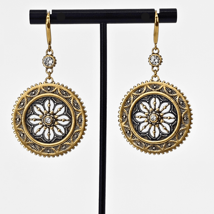 Gold and silver earrings on a black stand against a white background