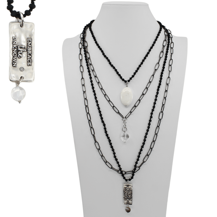 Necklace with multiple chains and pendants on a mannequin bust, with a pendant labeled 'Embrace Unknown' on the left.