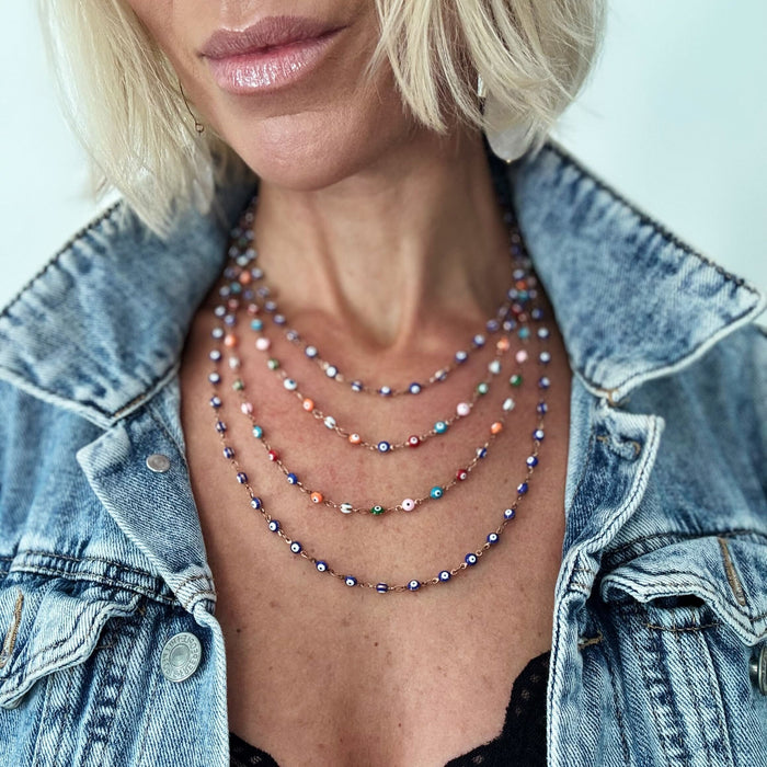 Woman wearing a denim jacket and colorful beaded necklaces against a light background