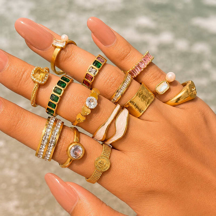 Gold Steel Cubic Zirconia Ring shown among assorted gold-tone rings with colourful stones and varied band designs