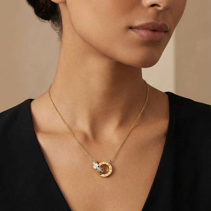 Gold Steel Necklace with a fine gold-tone chain and circular pendant featuring a small dark accent