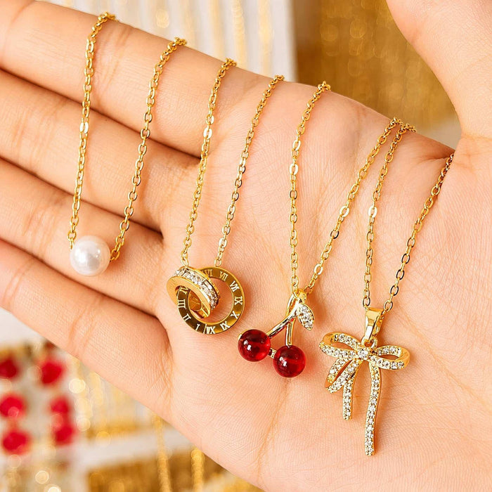Gold Steel Necklace chains in gold-tone metal feature pearl, Roman numeral, red cherry and crystal bow pendants
