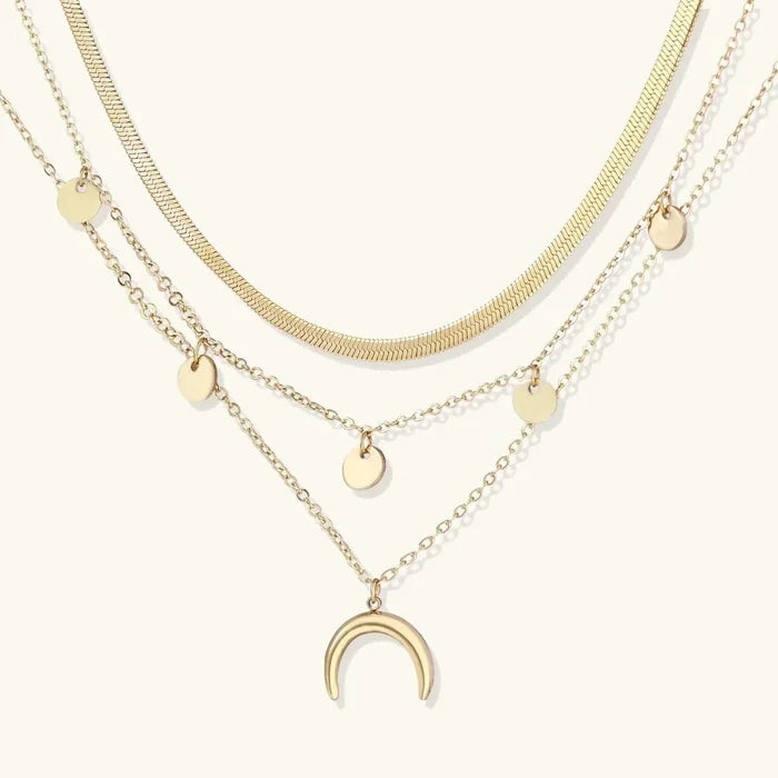 Golden Crescent Layered Necklace with three gold-tone chains, a flat herringbone strand, disc accents and an open crescent pendant