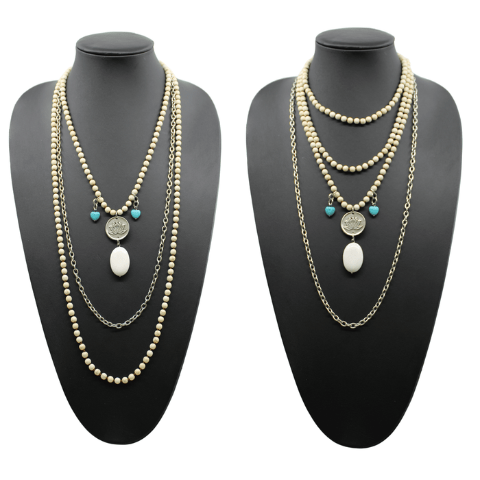 A person wearing a black shirt and showcasing a long gold chain necklace with off-white and blue howlite stones, along with matching bracelets and earrings.