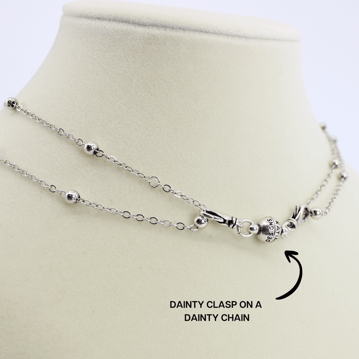 Silver necklace with a dainty clasp on a beige mannequin bust.