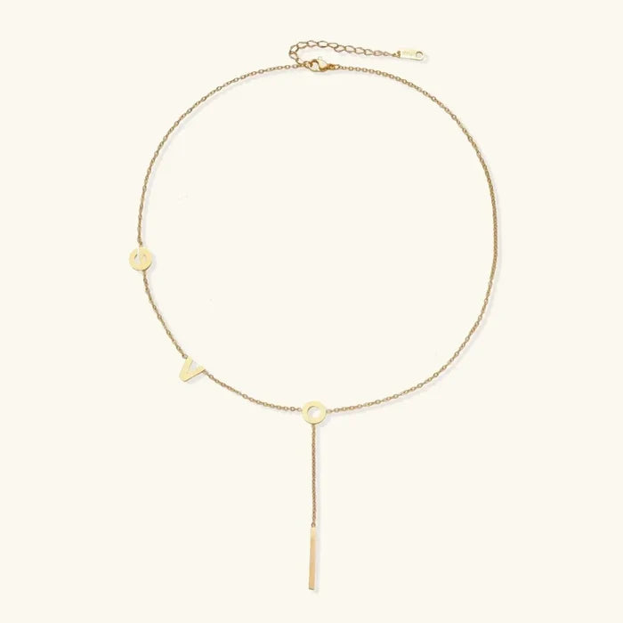 Love Letter Lariat Necklace in gold-tone metal with a fine chain, small letter charms, and a slim vertical bar pendant