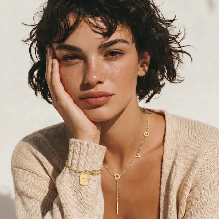 Love Letter Lariat Necklace in gold-tone metal with a fine chain, letter charms, and a slim vertical bar pendant