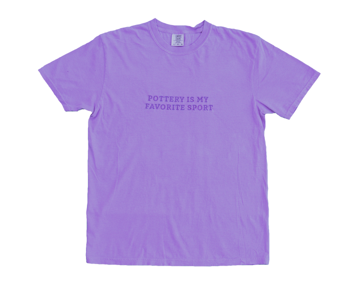 A purple t-shirt with the text 'Pottery Is My Favorite Sport' embroidered on the front.